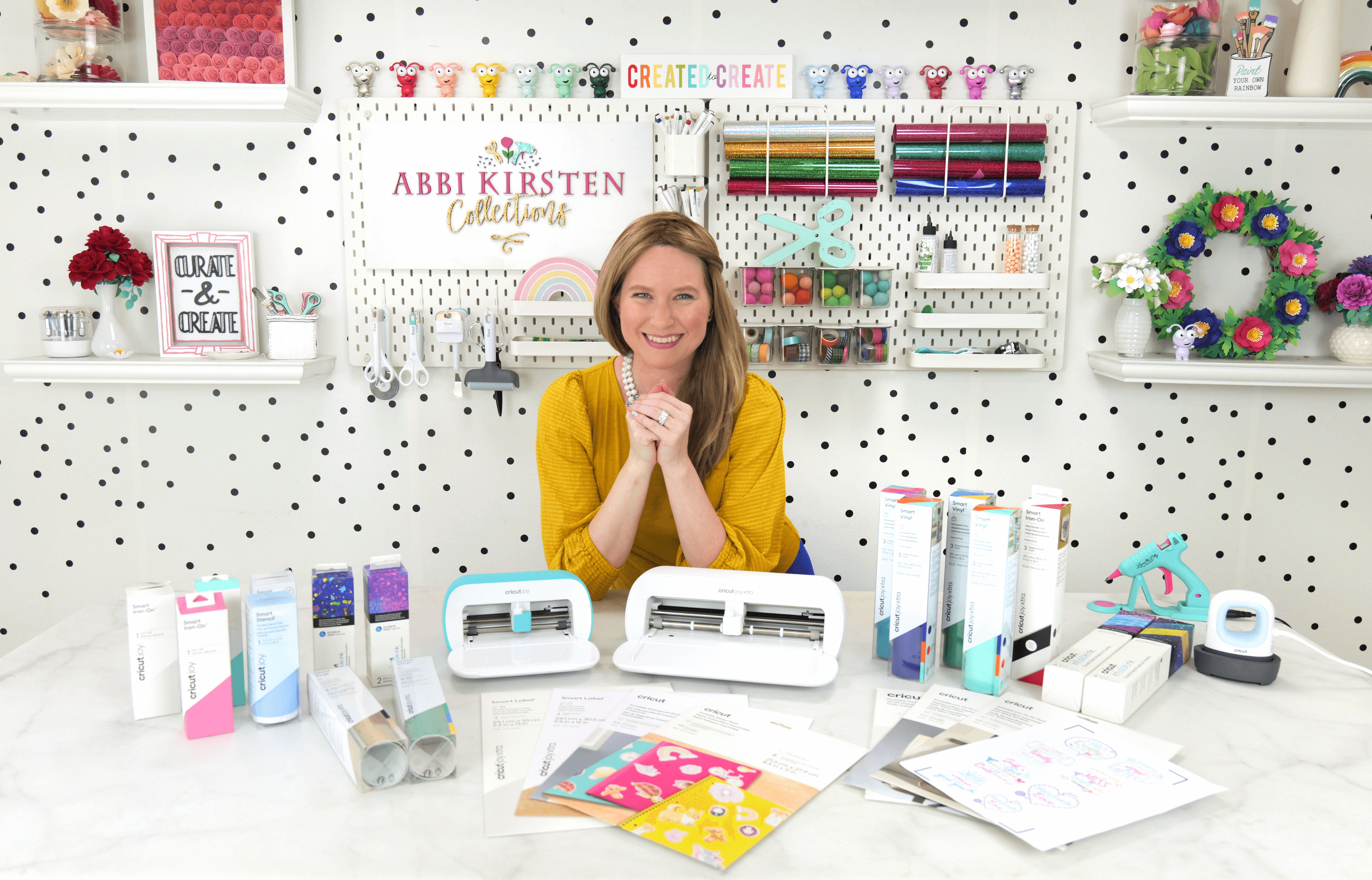 Abbi Kirsten with craft materials and cricut joy machines on a craft table.