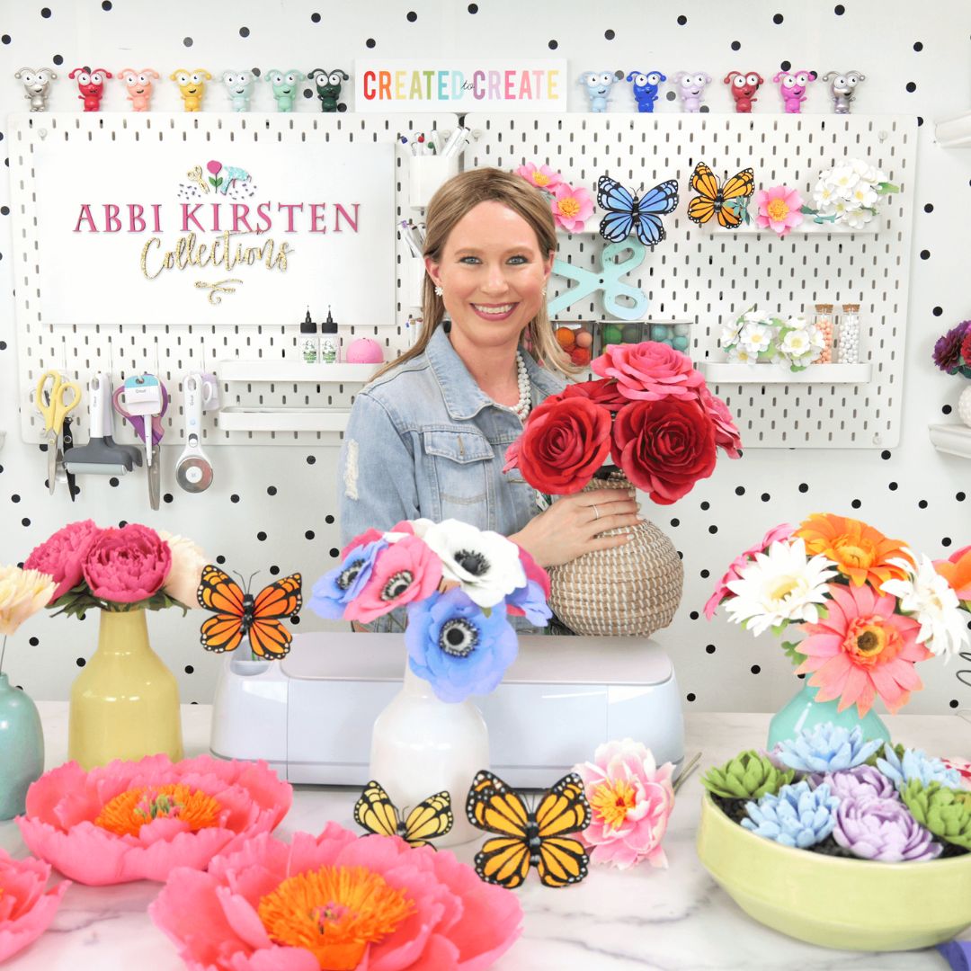 Abbi Kirsten with crepe paper flowers in front of a desk