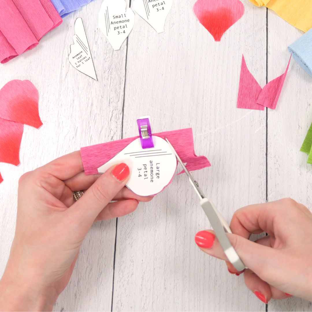 Cutting crepe paper petals with a pair of scissors
